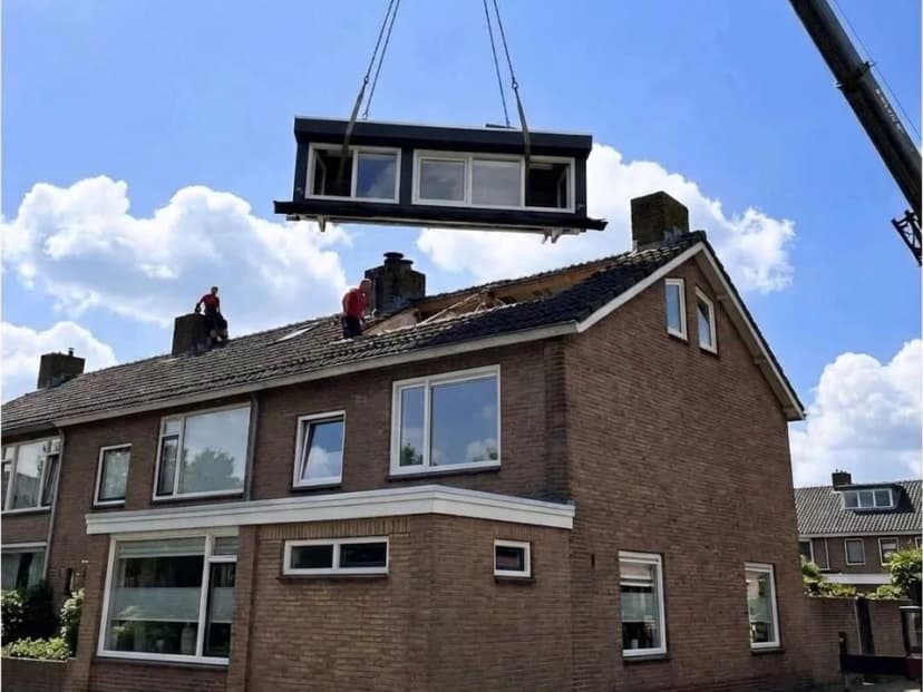 Prefab dakelement wordt met een kraan op het dak van een hoekwoning gehesen