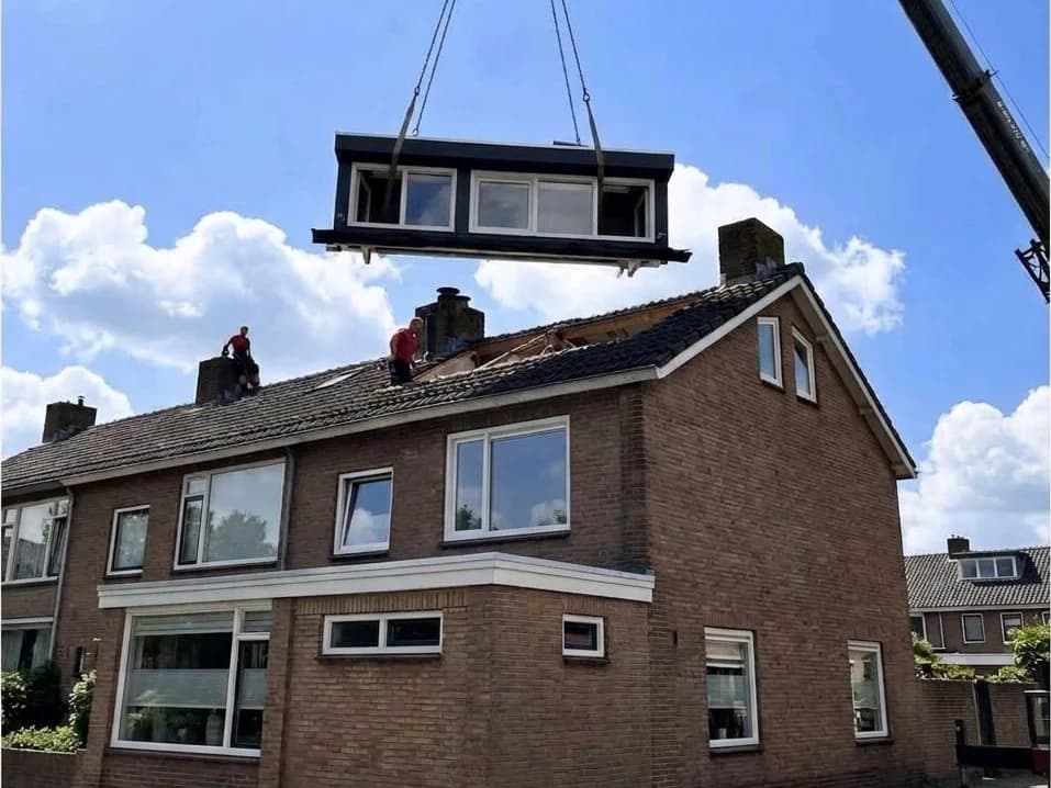 Prefab dakelement wordt met een kraan op het dak van een hoekwoning gehesen